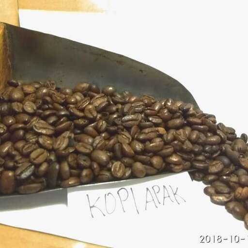 a large metal spoon filled with coffee beans.