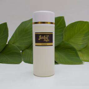a white candle with gold trim and a black label on the label.