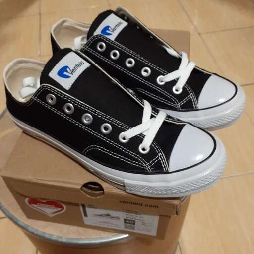 a pair of black and white shoes on a cardboard box.