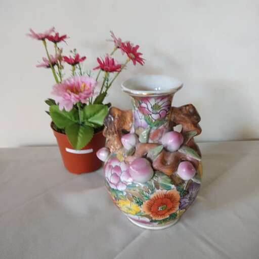 a vase with flowers and a pot with a plant in it.