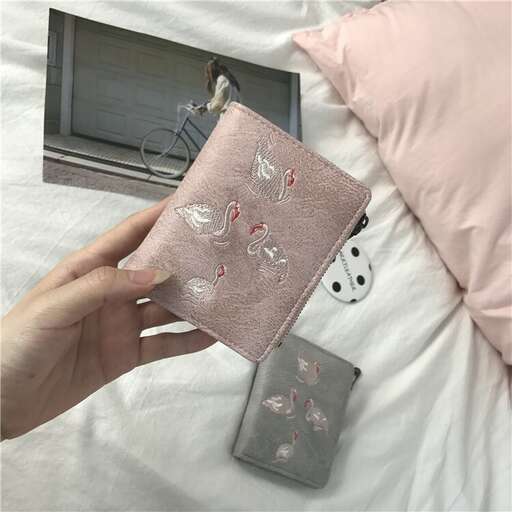 a hand holding a closed wallet with a picture of a bird on it.